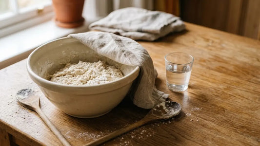 Mélange de farine et d'eau au repos dans un bol en céramique à moitié couvert d'un torchon