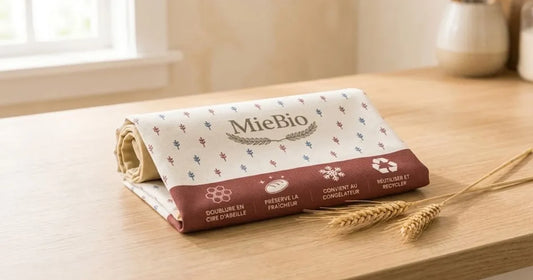Sac à pain MieBio plié à plat sur un plan de travail avec des épis de blé