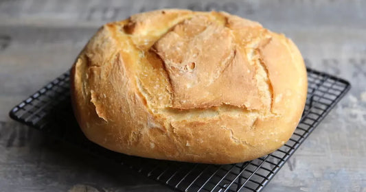 Pain maison rond sorti de cocotte posé sur une grille