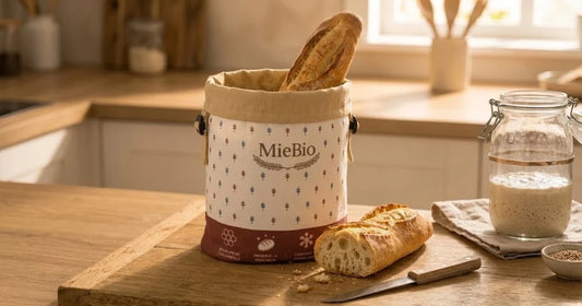 Baguette dans le sac à pain MieBio à côté d'un bocal de levain et d'un pain tranché