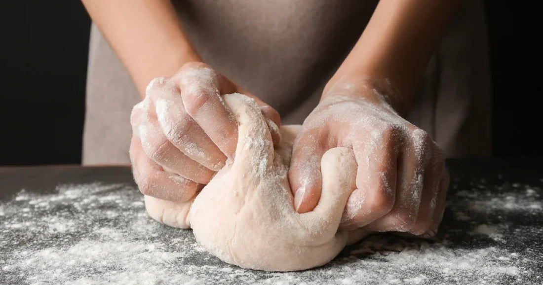 Mains pétrissant une pâte à pain sur un plan fariné